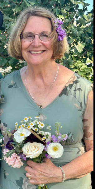 Mary smiling outdoors while holding a bouquet of flowers.